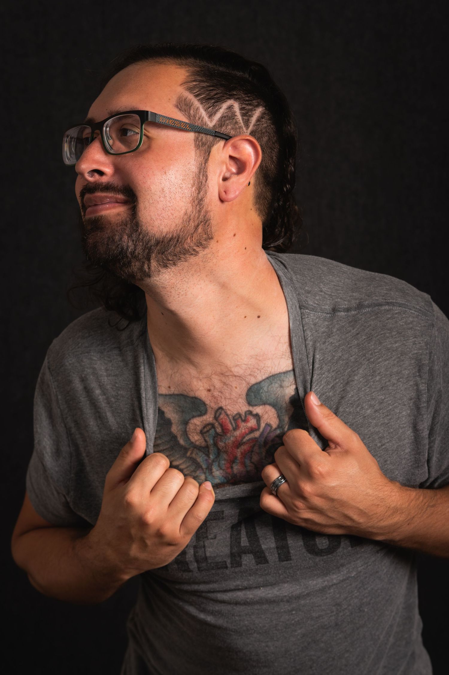 Portrait of a person in glasses and gray shirt showing tattoos.