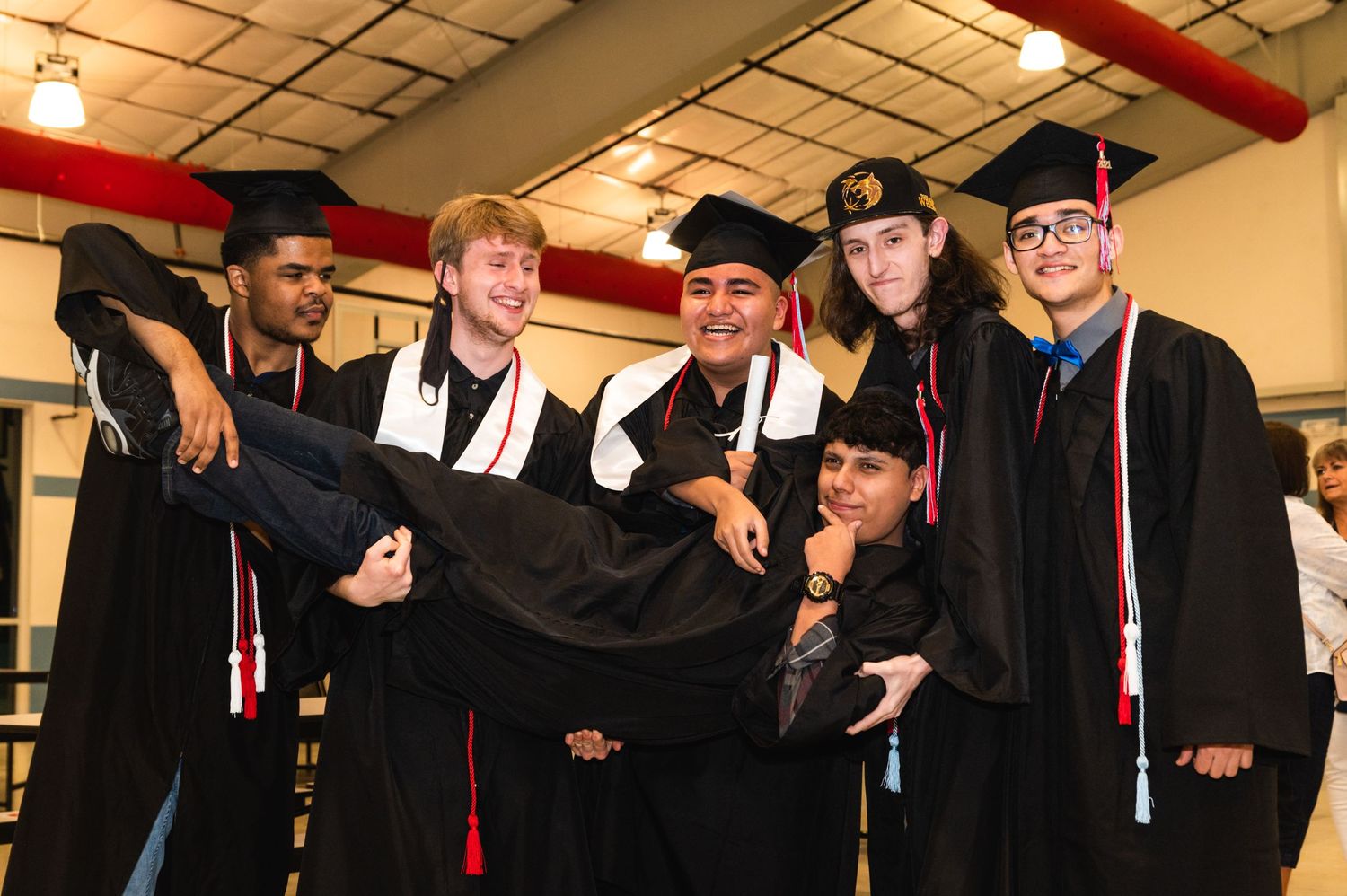 Graduates in black caps and gowns having fun posing for a group photo.