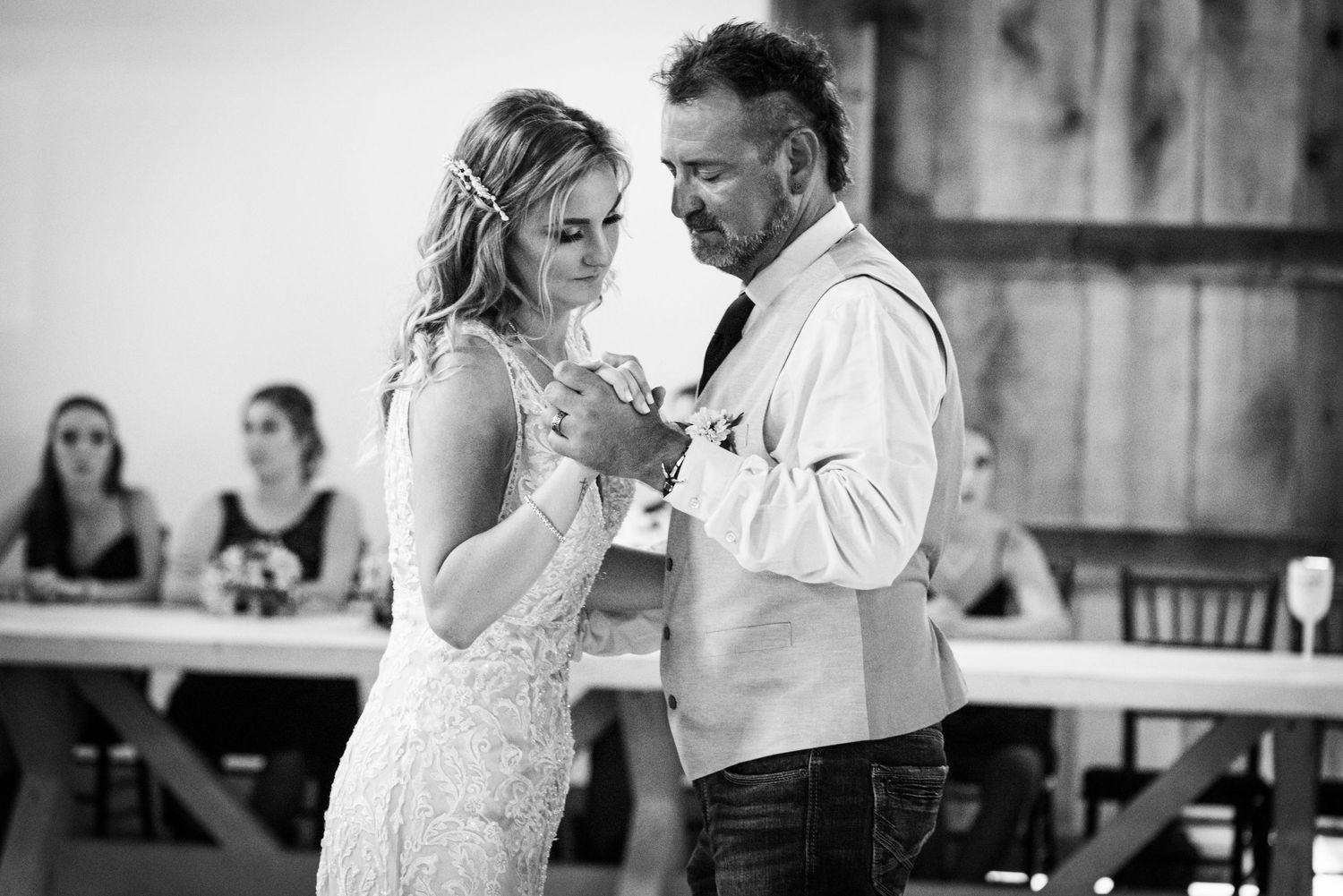Black and white capture of intimate slow dance at rustic wedding reception.
