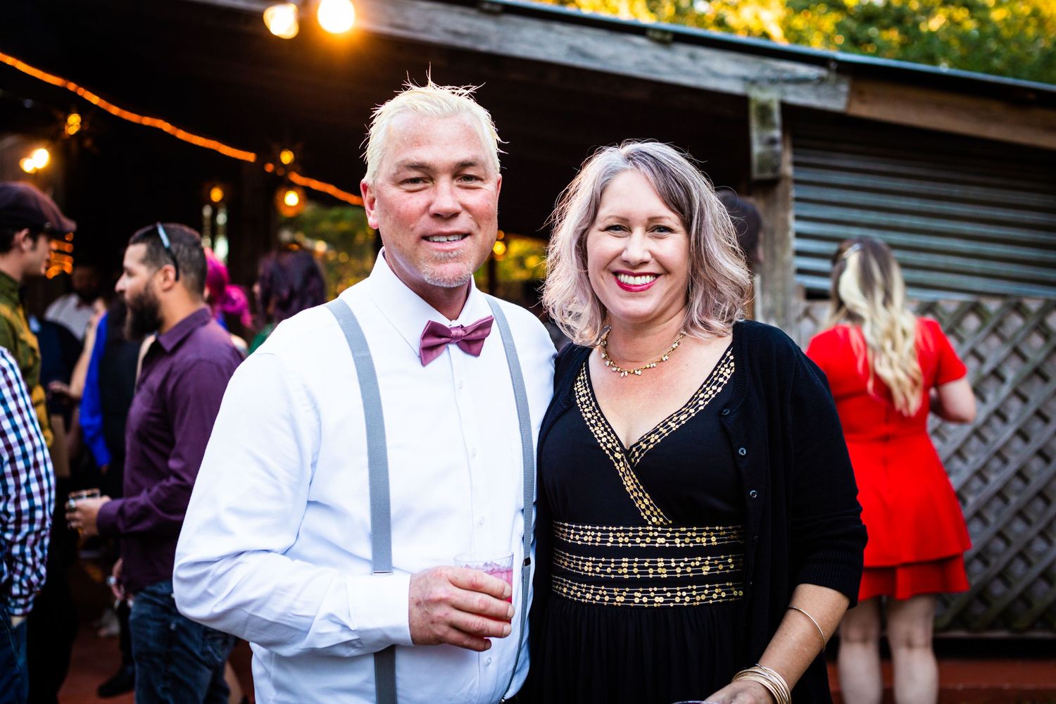 Couple dressed in formal attire enjoying evening outdoor wedding reception.