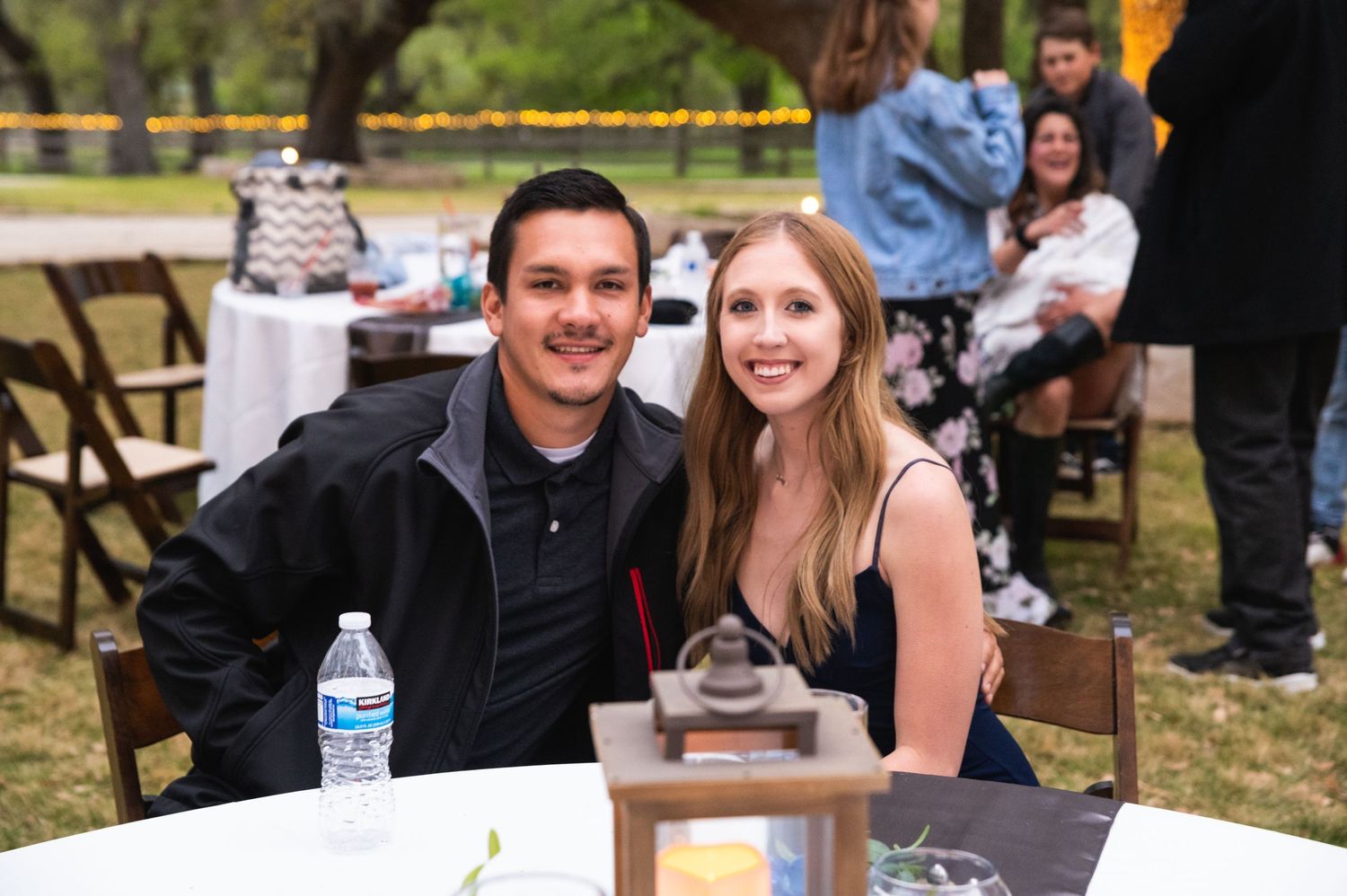 Couple sitting at outdoor table during casual celebration event.