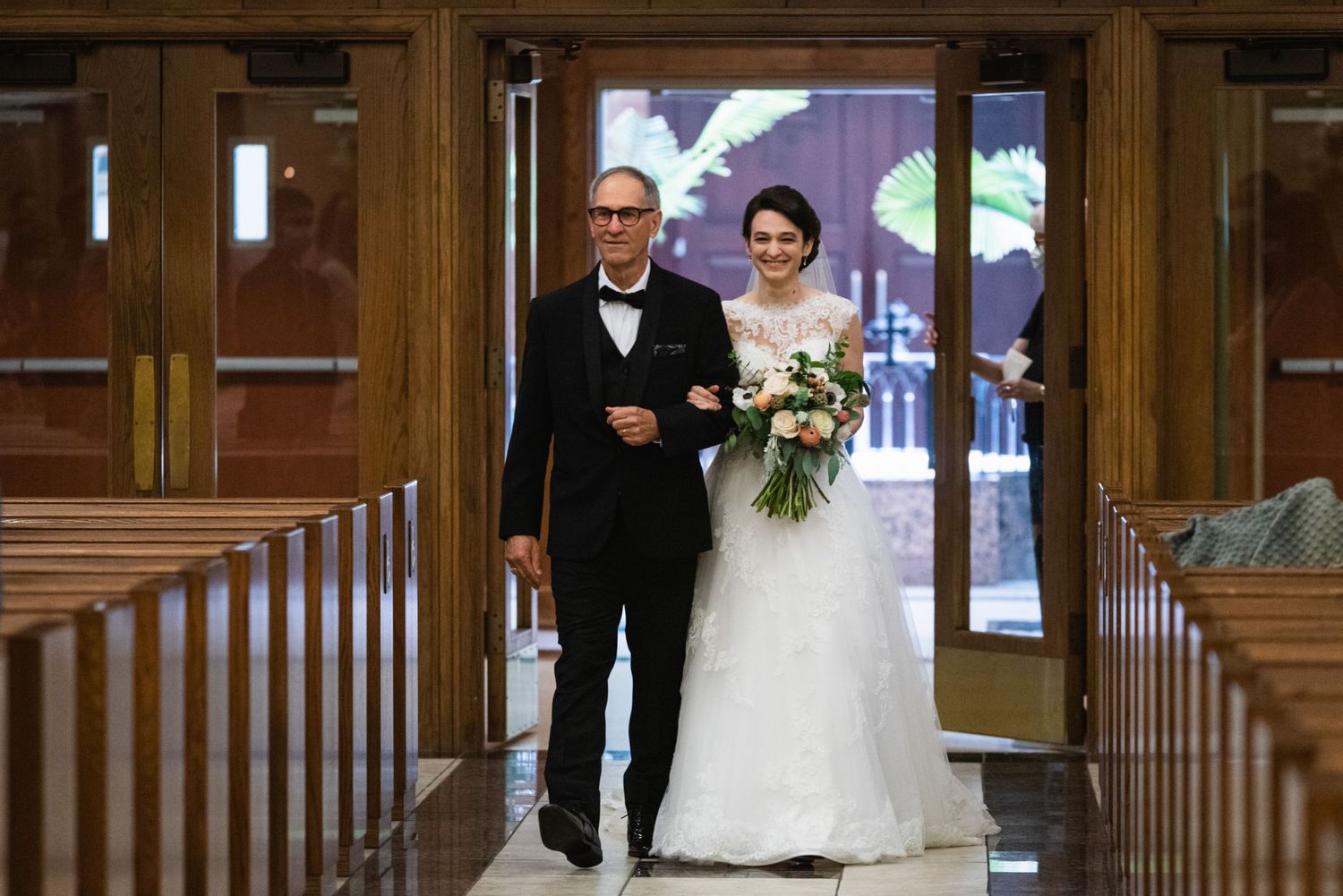 Wedding ceremony processional in classic church interior with wooden details and natural lighting.