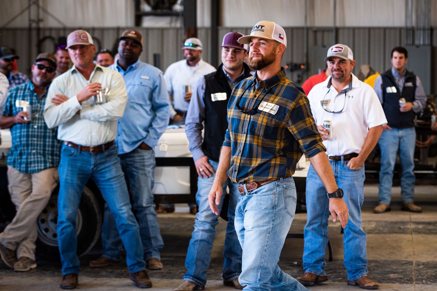 Group of workers in casual attire standing together at industrial site.