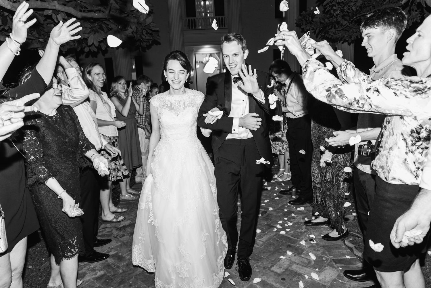 Wedding couple walking through confetti shower during evening reception exit.