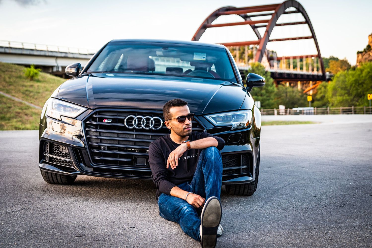 Modern Audi S3 with aggressive front grille positioned near architectural bridge structure.