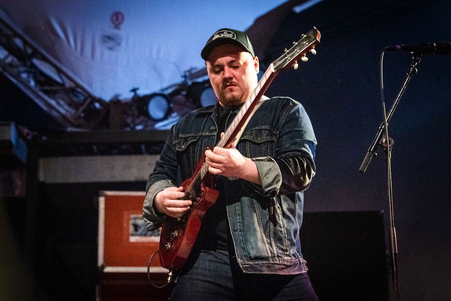 Live performance of guitarist playing mahogany guitar against blue stage lighting.