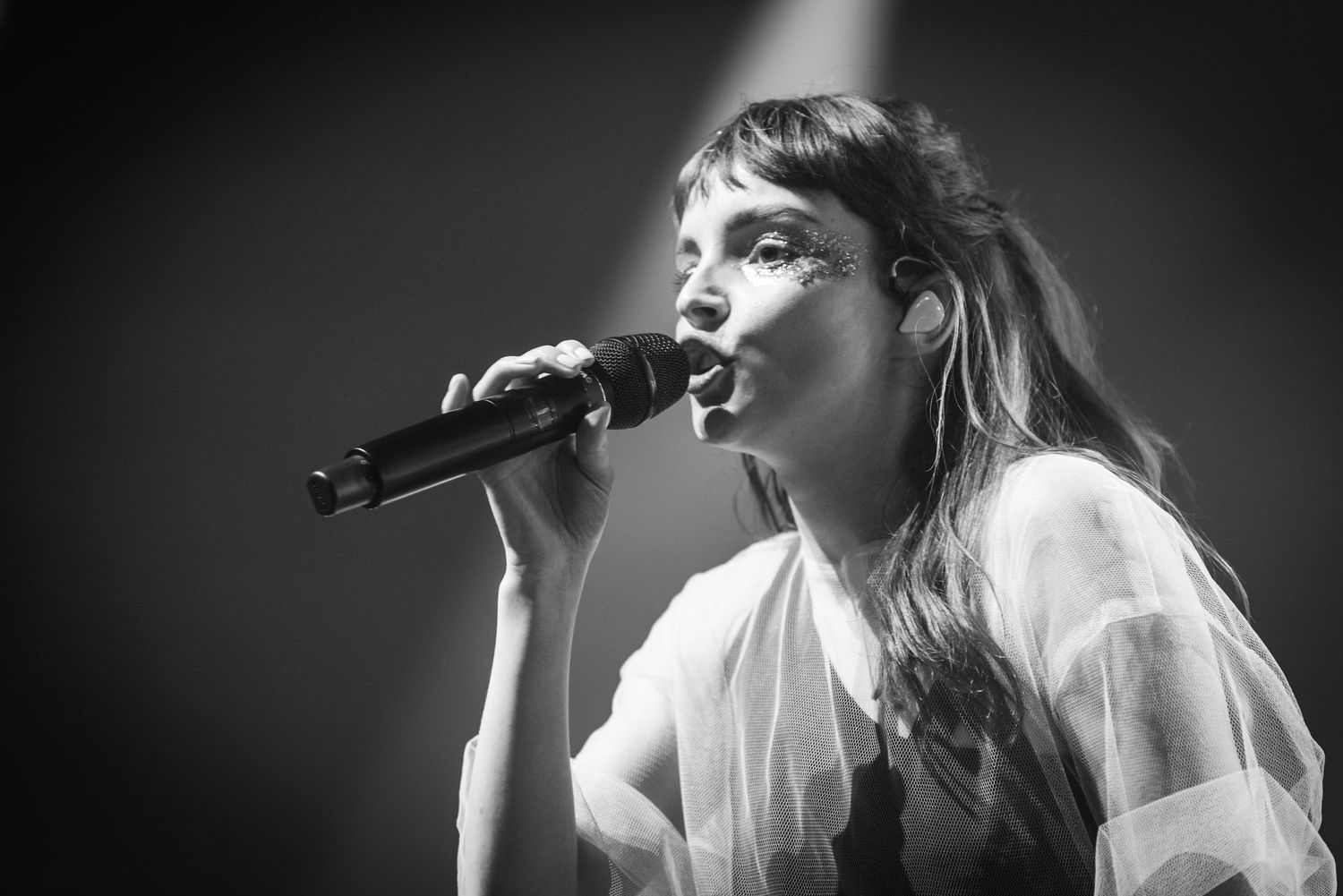 Black and white shot of singer performing passionately on stage with dramatic lighting.