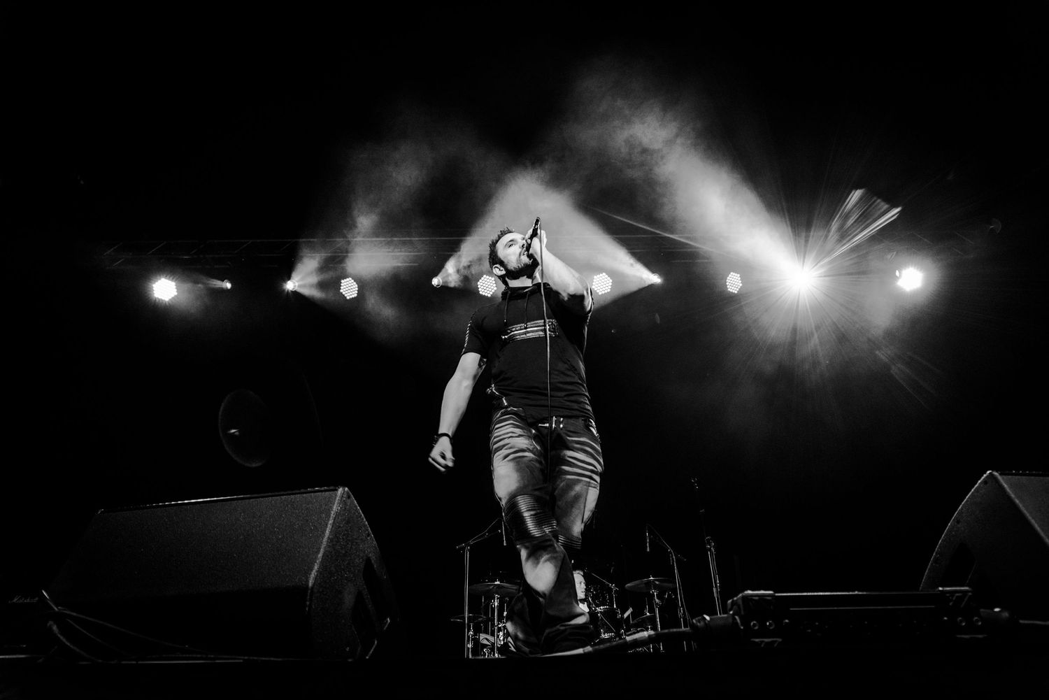 Dynamic black and white concert photo captures performer's silhouette against bright stage lights.