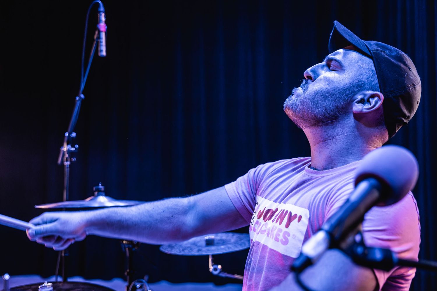 Passionate drummer performing with intensity during live music concert.