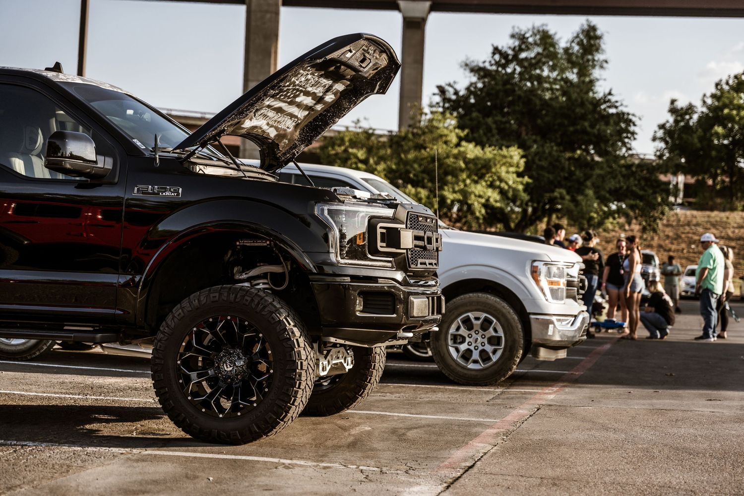 Lifted black Ford F150 truck with custom wheels at a car show.