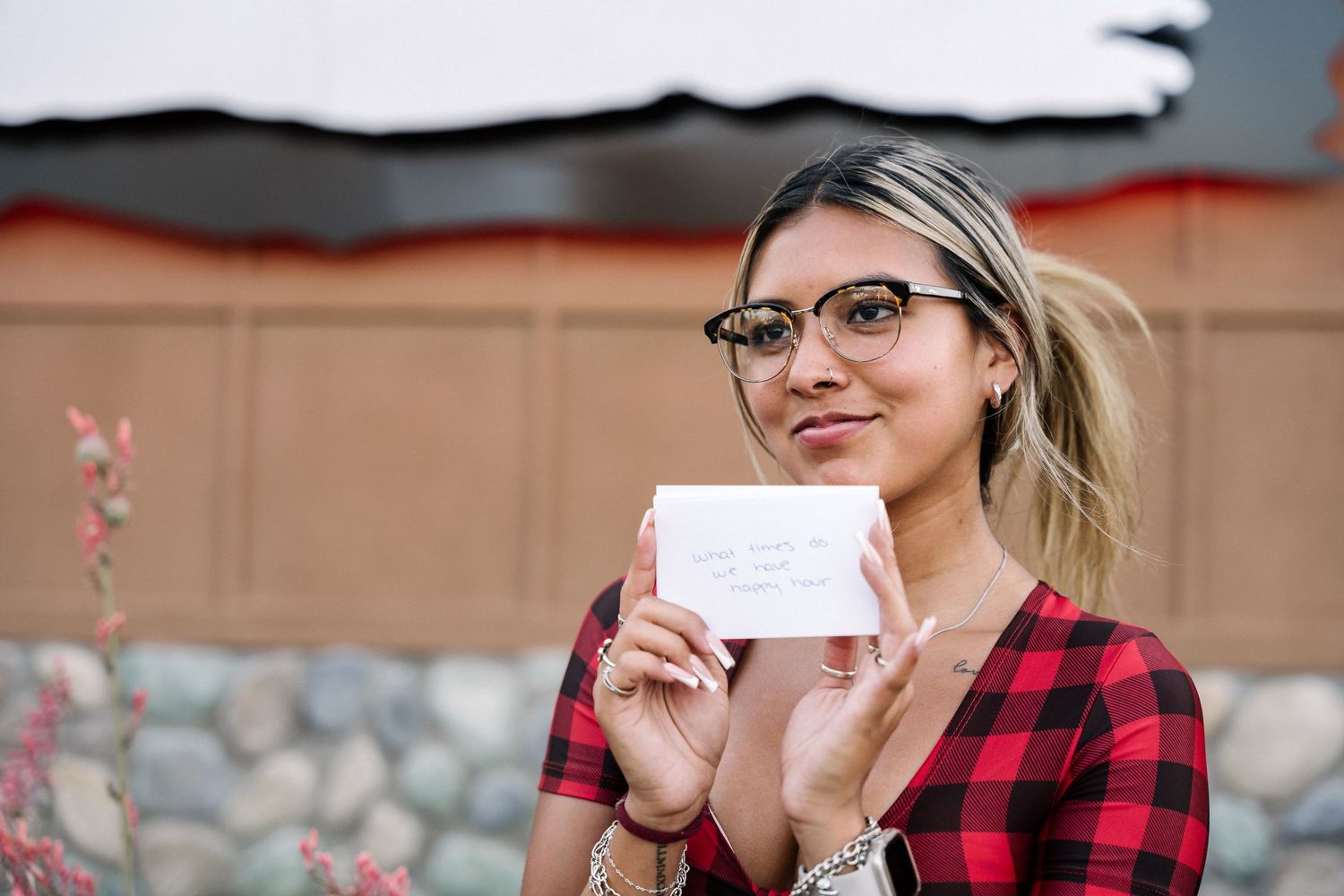 Person in plaid shirt holding up a white card while smiling at the camera.