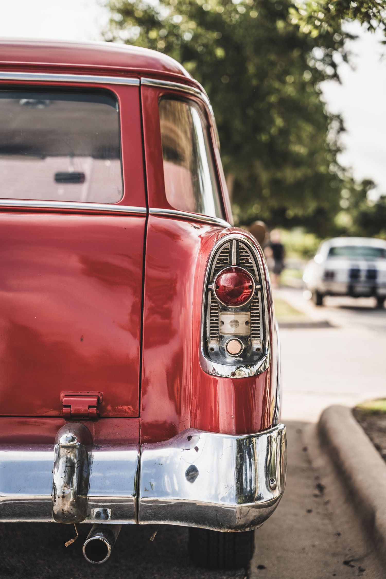 Rear taillight detail of a vintage red Chevrolet with chrome trim.