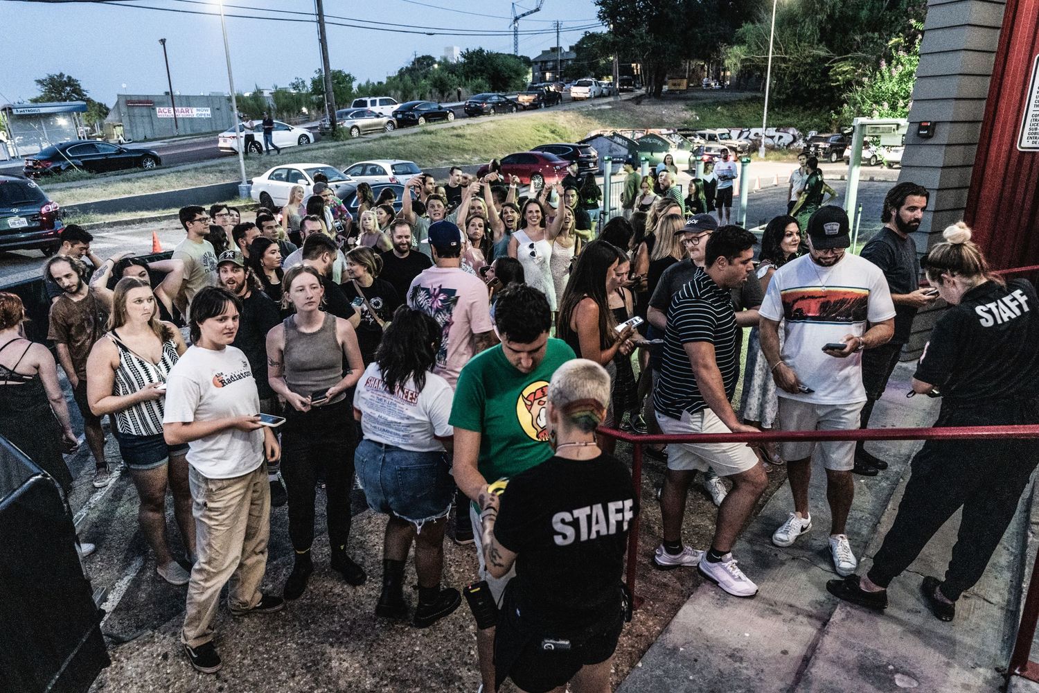 Large crowd of concert attendees waiting in line outside a venue entrance.