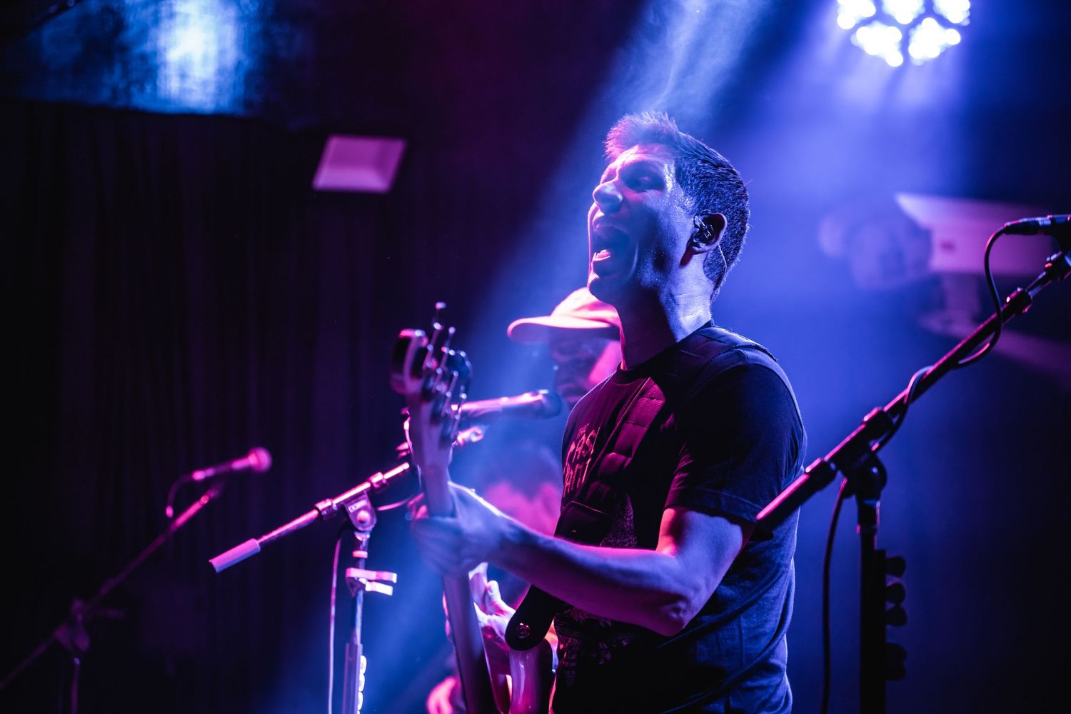 Musician performing on stage illuminated by dramatic blue concert lighting.