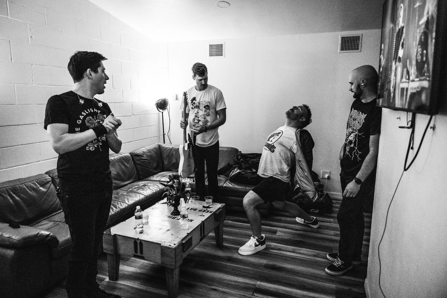 Black and white photo of musicians hanging out in a backstage room.