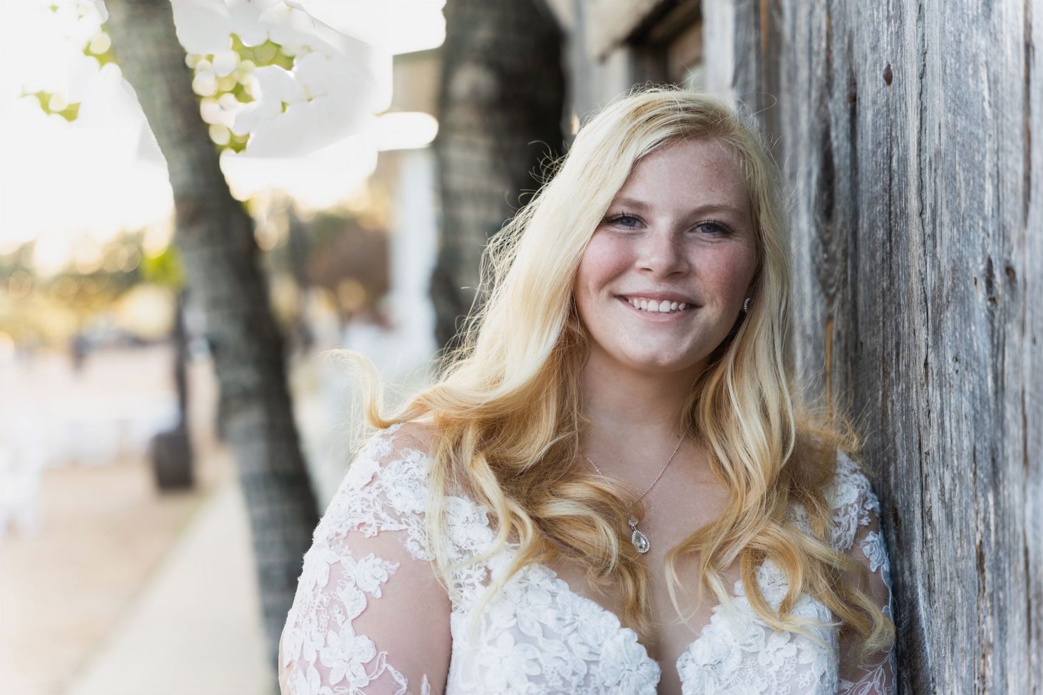 Elegant bridal portrait against weathered wooden column with natural lighting.