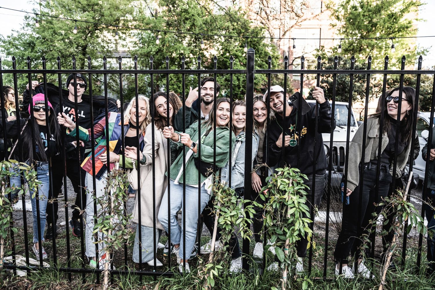 Large crowd of music fans gather behind metal fence at outdoor concert venue.