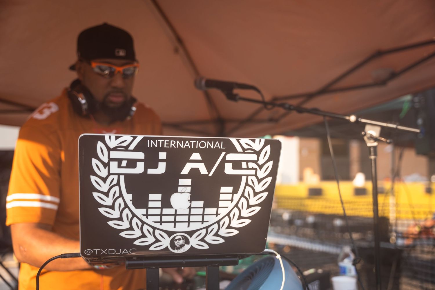 Close-up of a DJ laptop with International DJ A/C logo and graphic equalizer design.