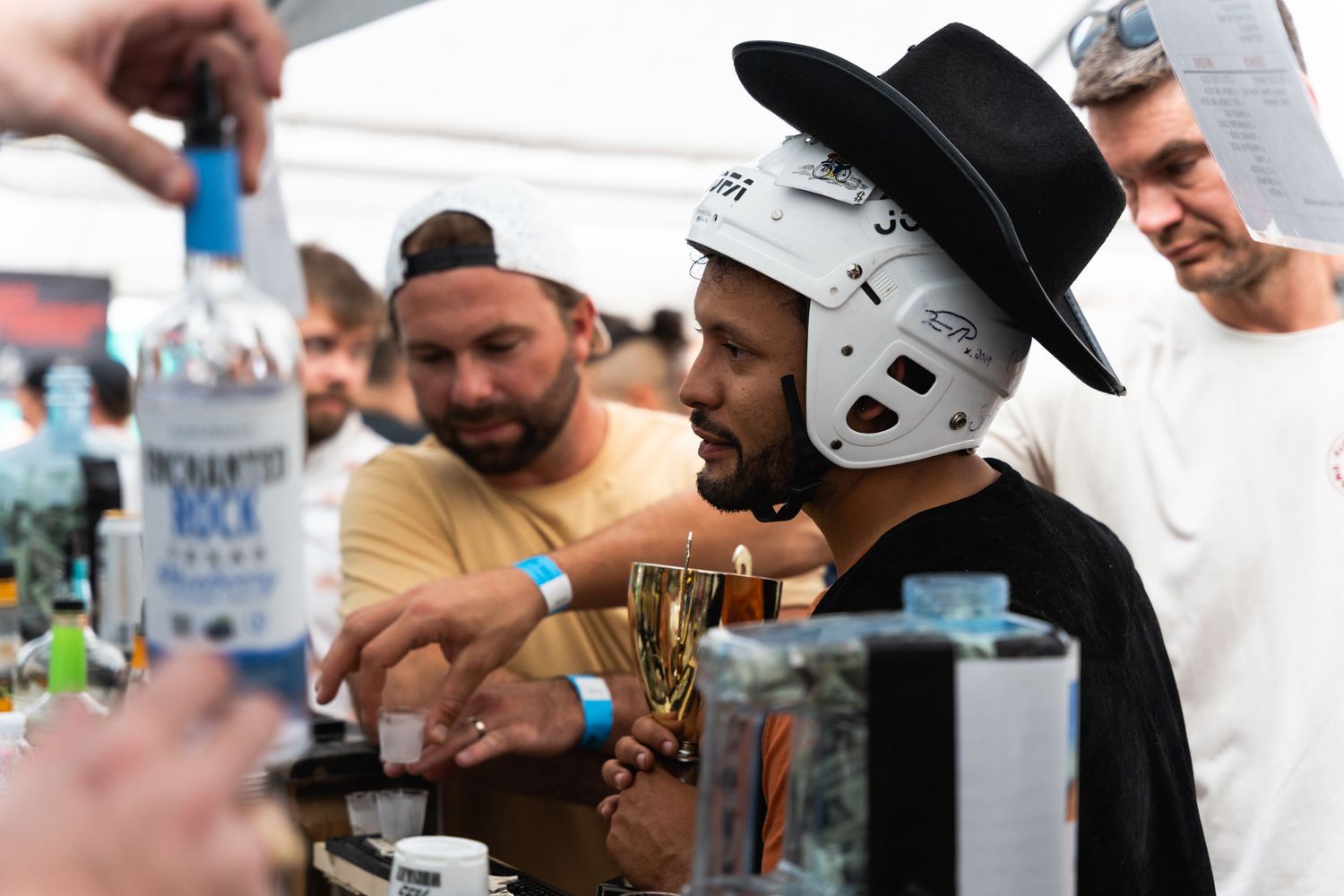 People pouring drinks at an outdoor bar event with unique costume accessories.
