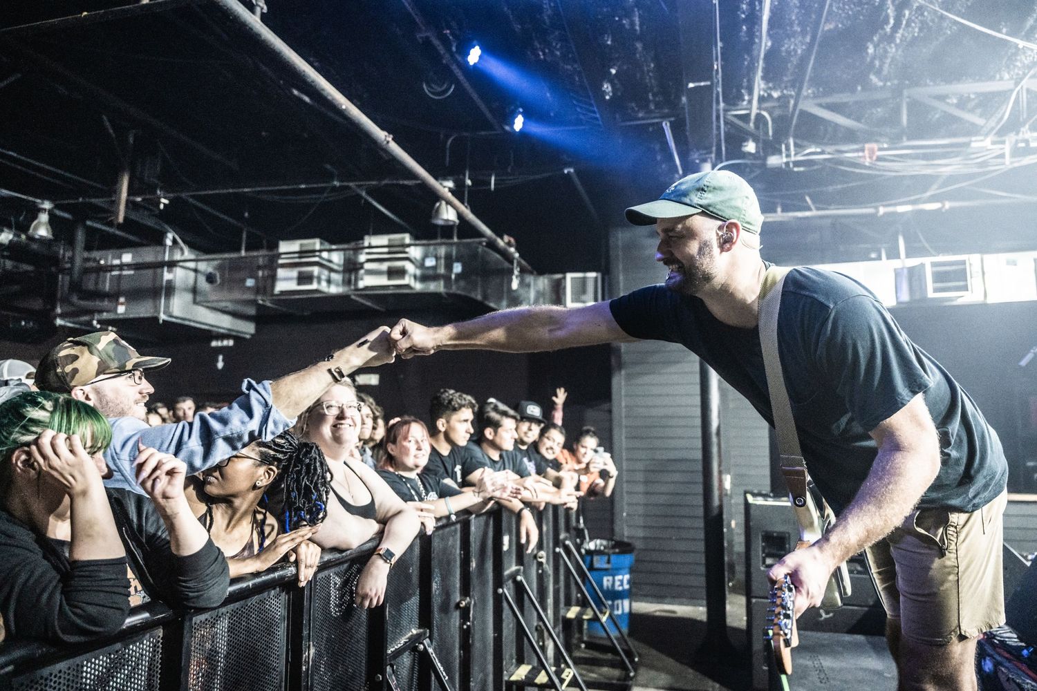 Performer leans into crowd barrier while engaging with enthusiastic fans during live show.