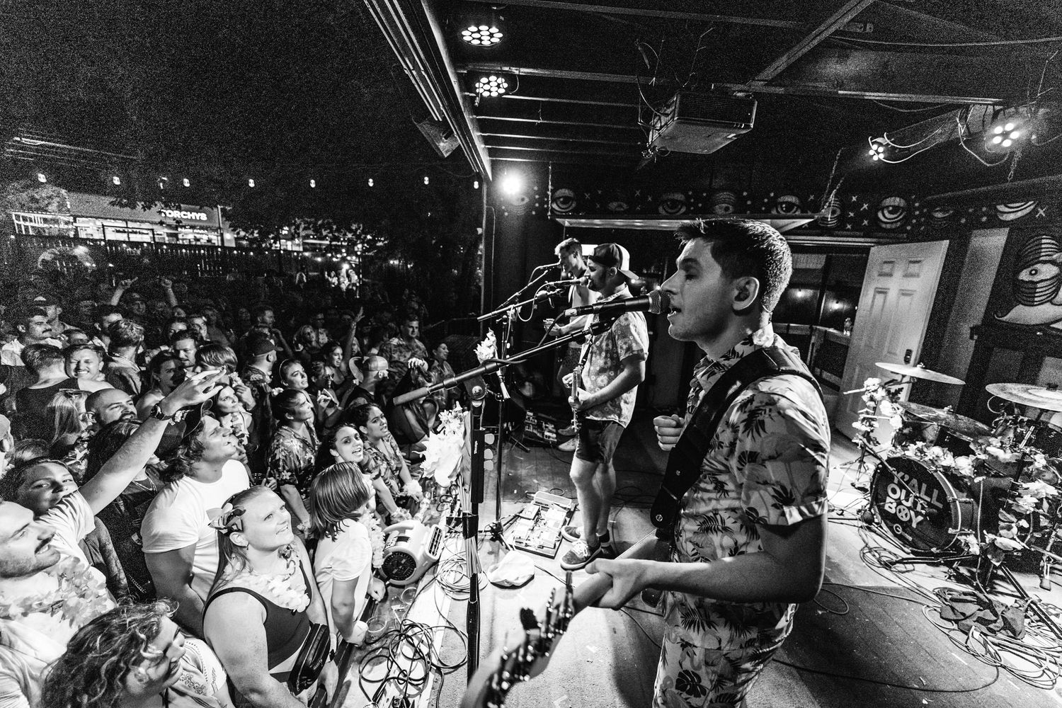 Black and white shot of energetic concert performance with crowd in background.