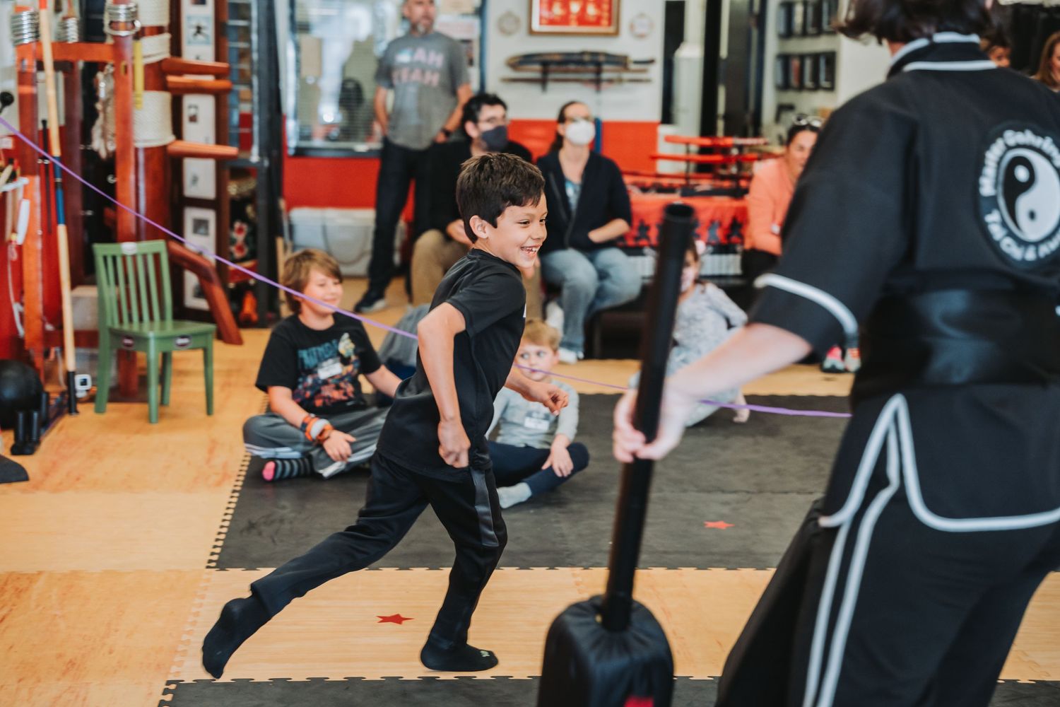 Student performs a martial arts stance during practice in a well-equipped training facility.