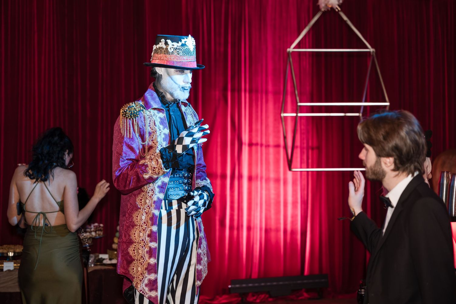 Performers on stage during a live theater show with red curtains and dramatic lighting in the background.