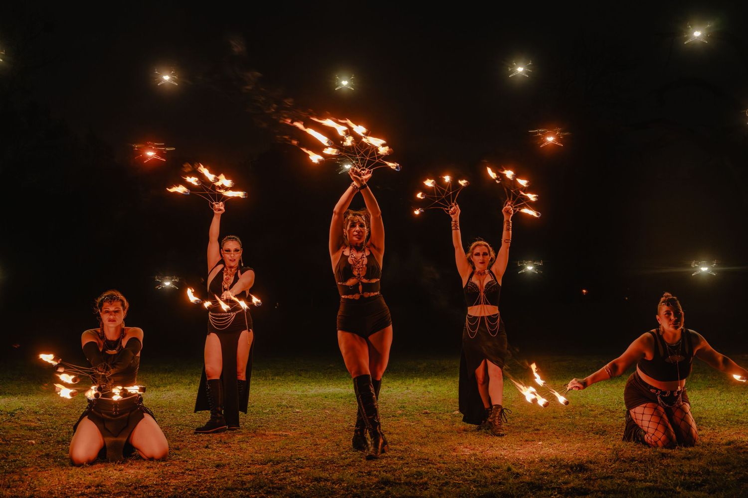 Five fire dancers perform a stunning nighttime show, wielding flaming props in a dramatic outdoor display.