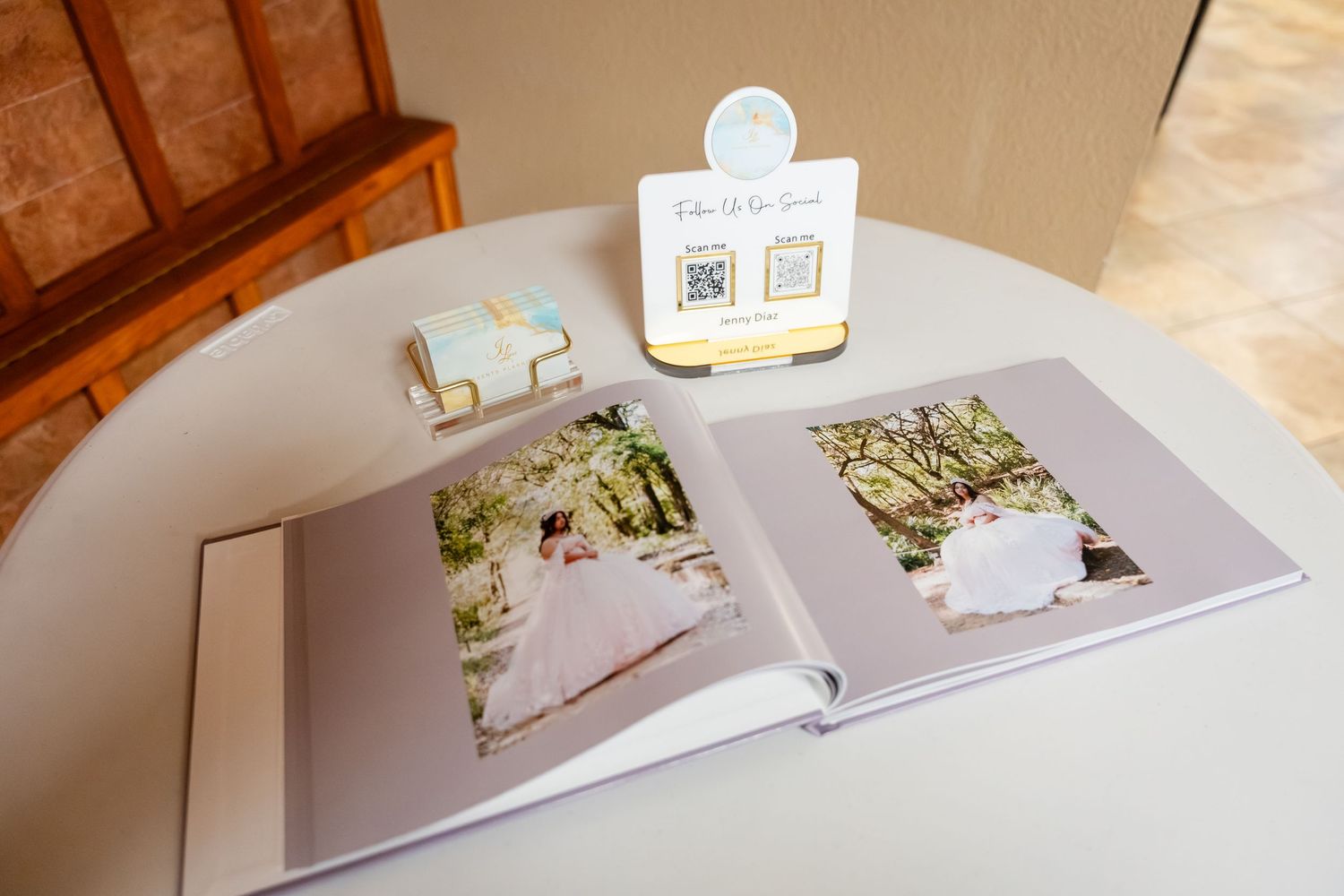 Open wedding photo album on a white table beside a QR code sign and decorative gift box at a reception.