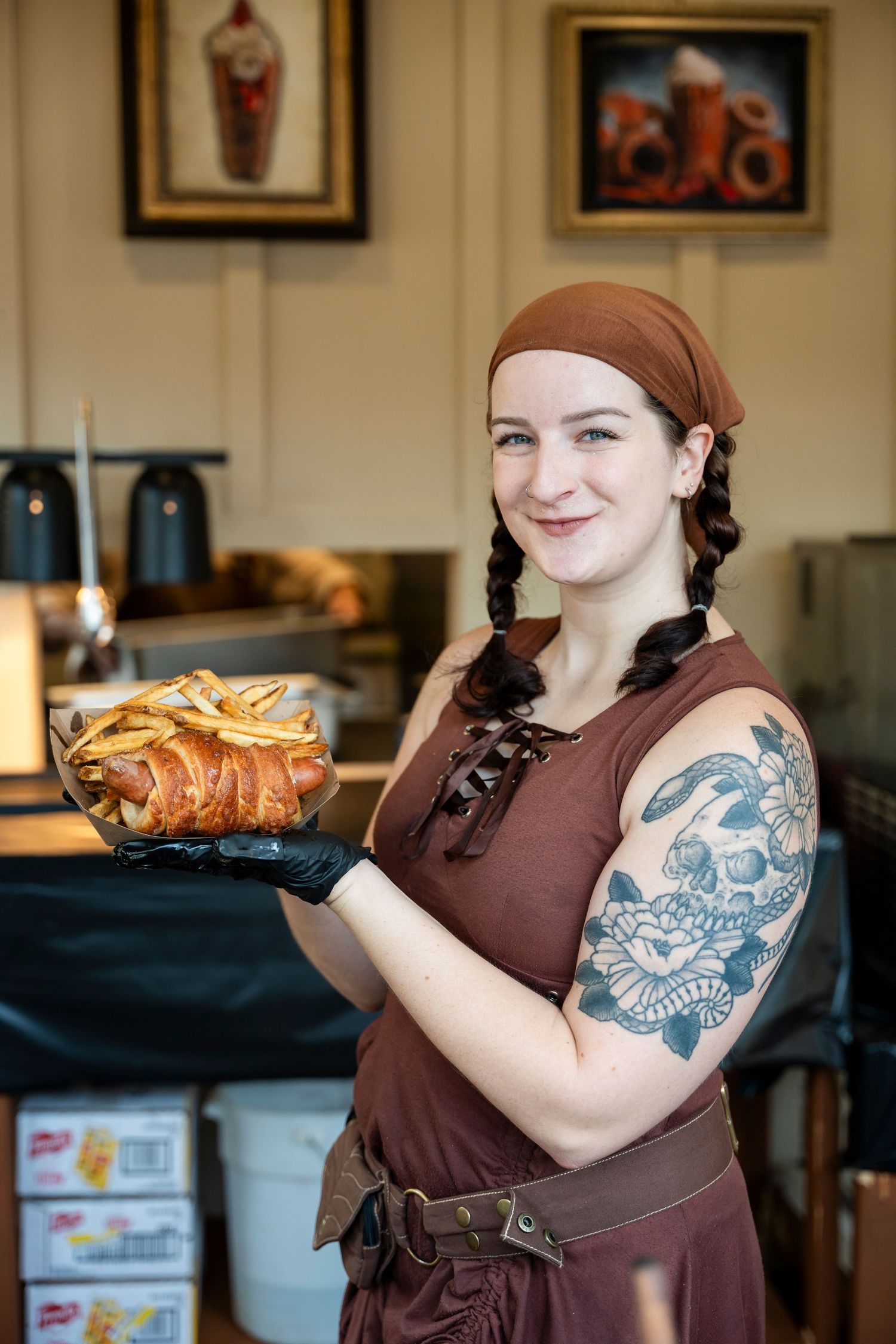 A person in a brown apron shows off their blue octopus arm tattoo in a kitchen setting.