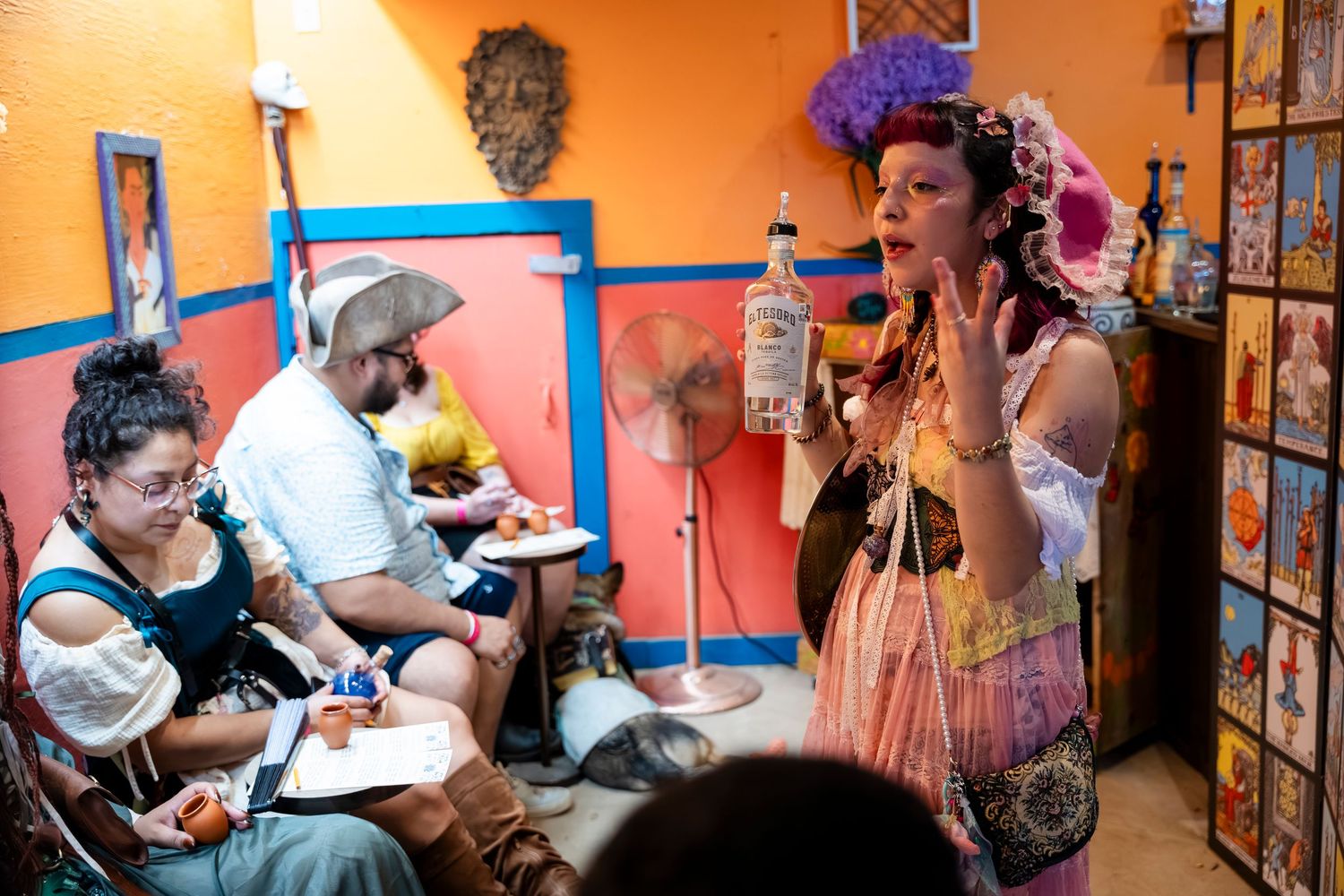 A group of people gather in an orange-walled room for an art workshop or creative session.