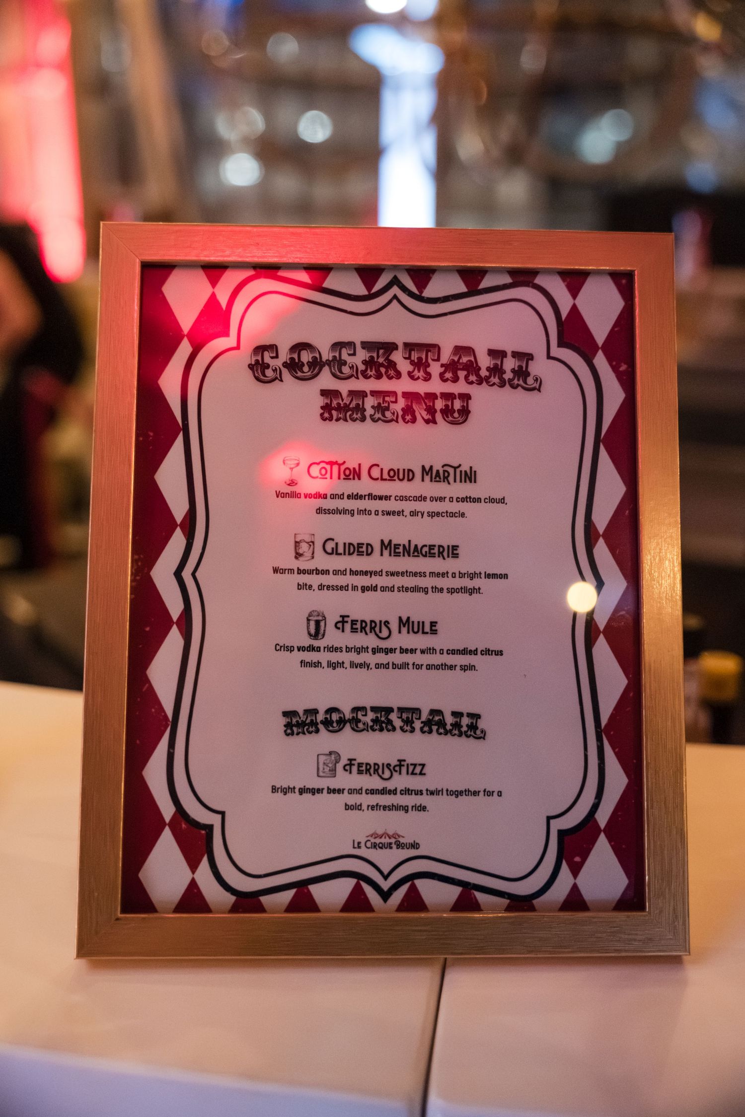 Close-up shots of printed menu cards with cocktail text in ornate frames displayed at an event.