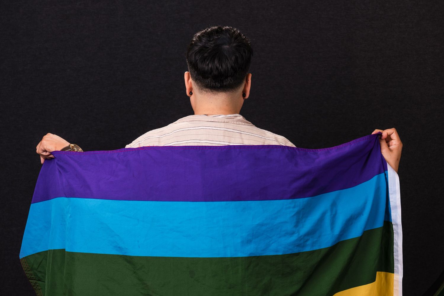 A row of pride flags being held up and waved during a pride celebration event.