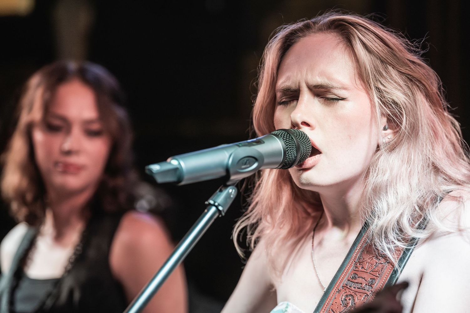 A performer sings into a microphone on stage during a live music performance.
