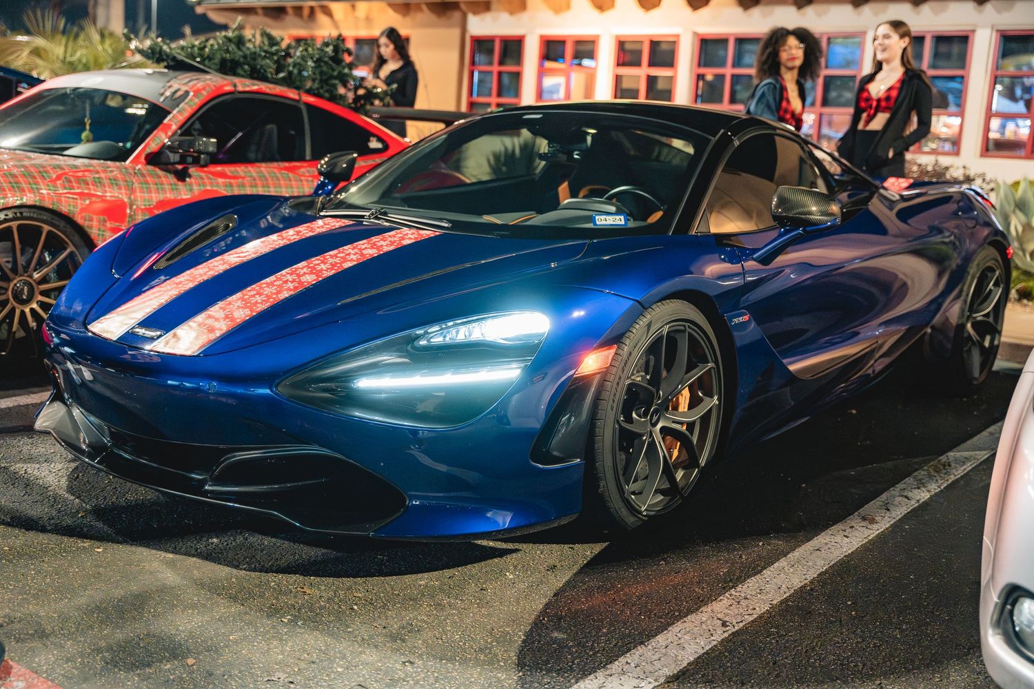 Blue McLaren 720S with racing stripes displayed at a nighttime car meet.