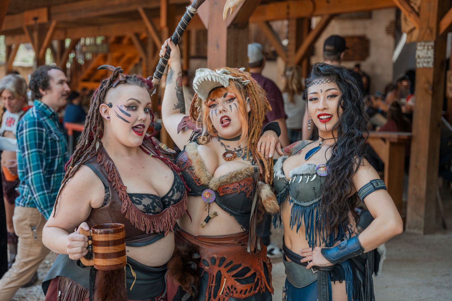 Three people in steampunk-inspired costumes pose energetically at a renaissance fair.