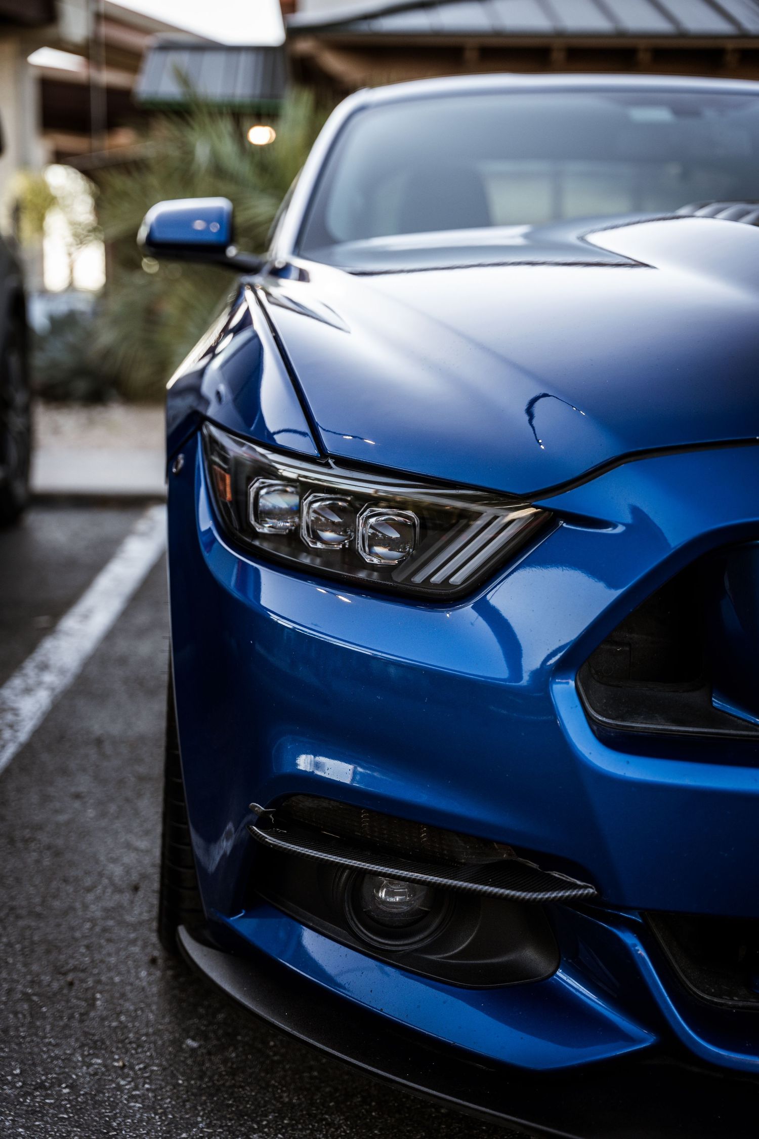 Close-up of a blue Ford Mustang's aggressive front headlight and grille design.