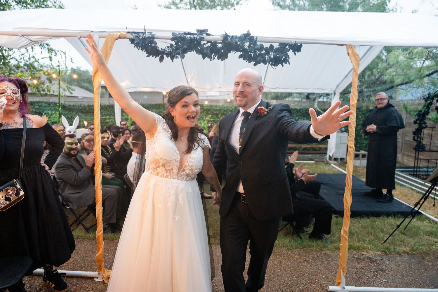 Newlyweds celebrate joyfully under a white tent during their wedding reception.