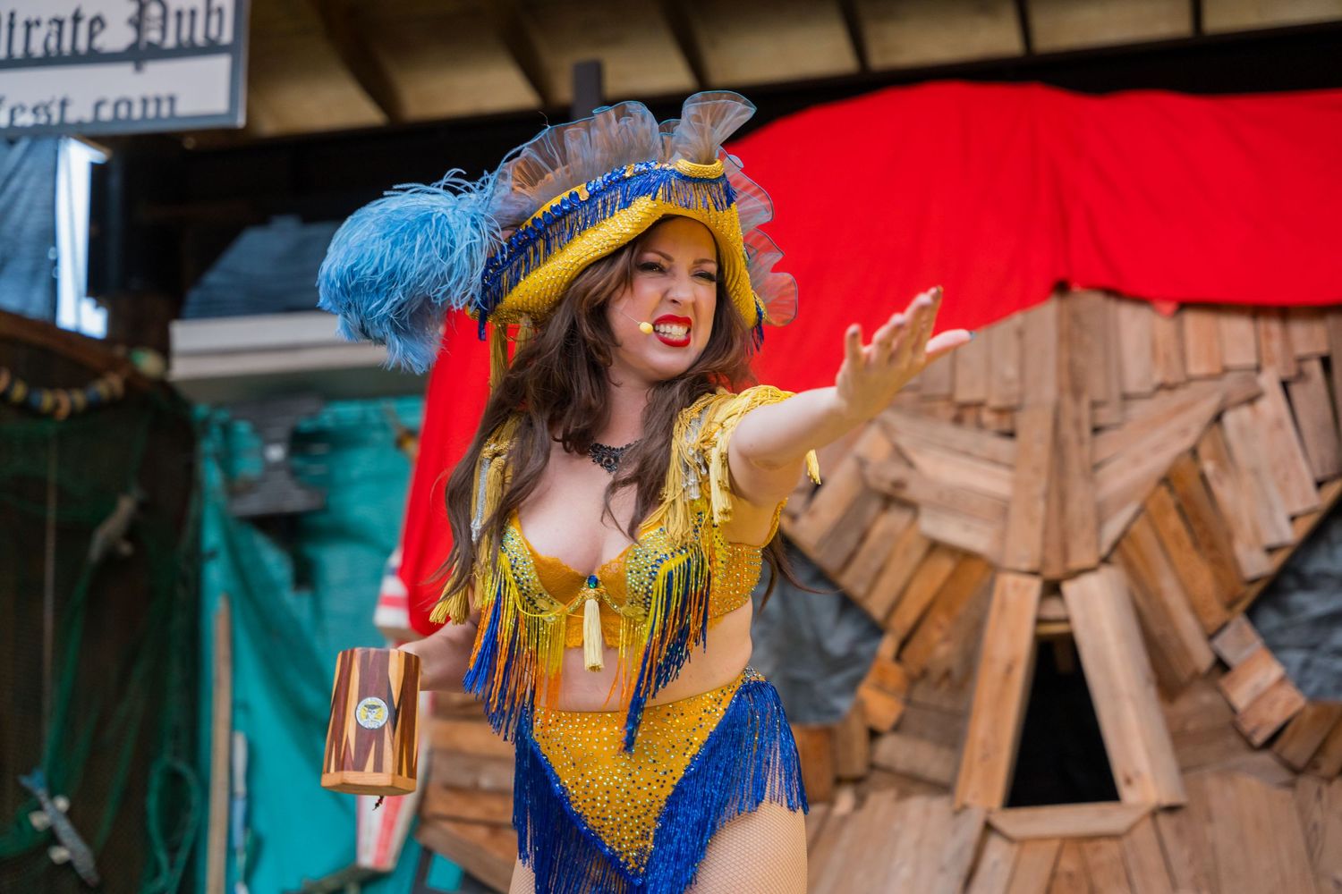 A performer in a blue and gold renaissance costume dances during a stage show.