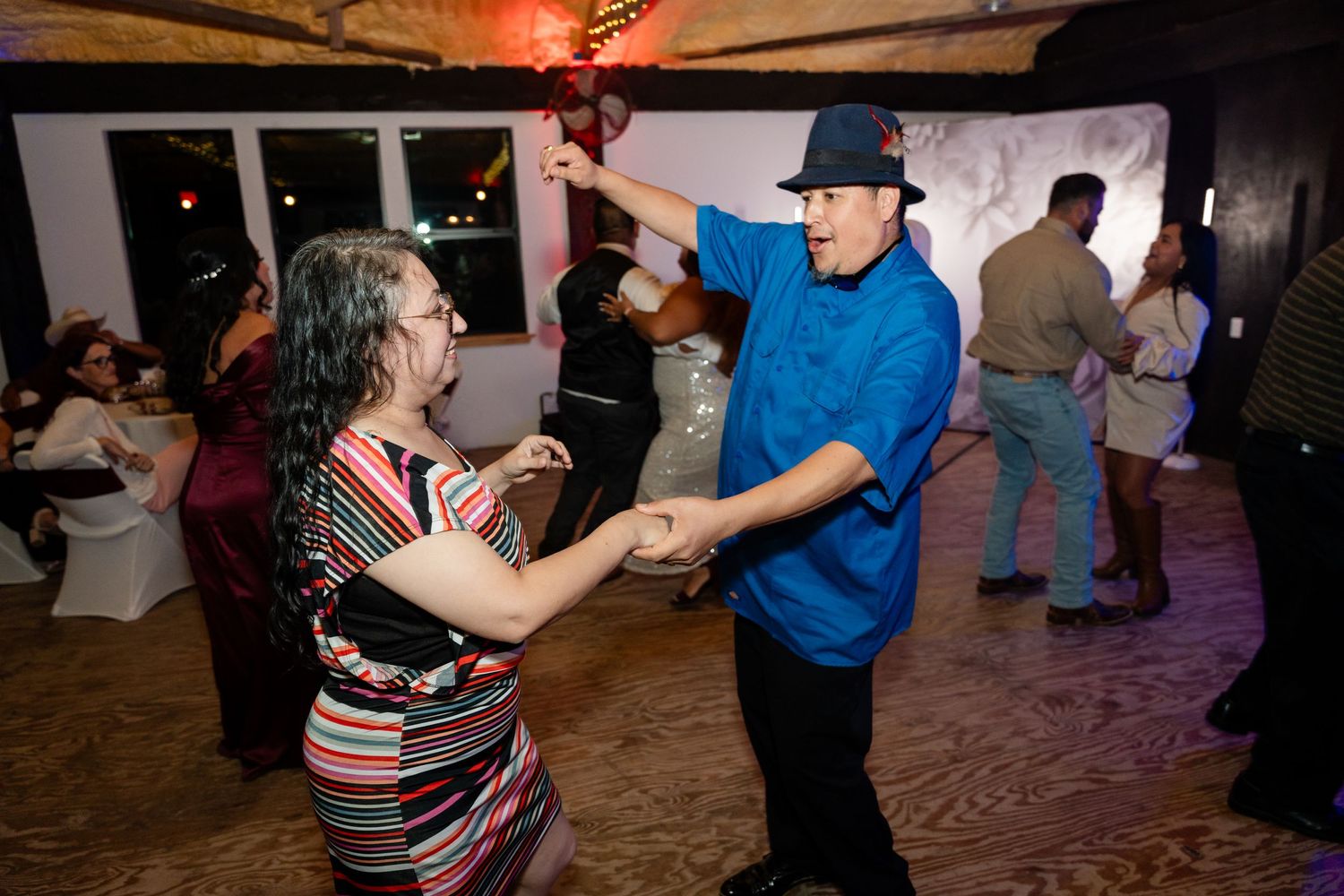 Wedding guests dance and enjoy themselves on the wooden dance floor during reception celebrations.