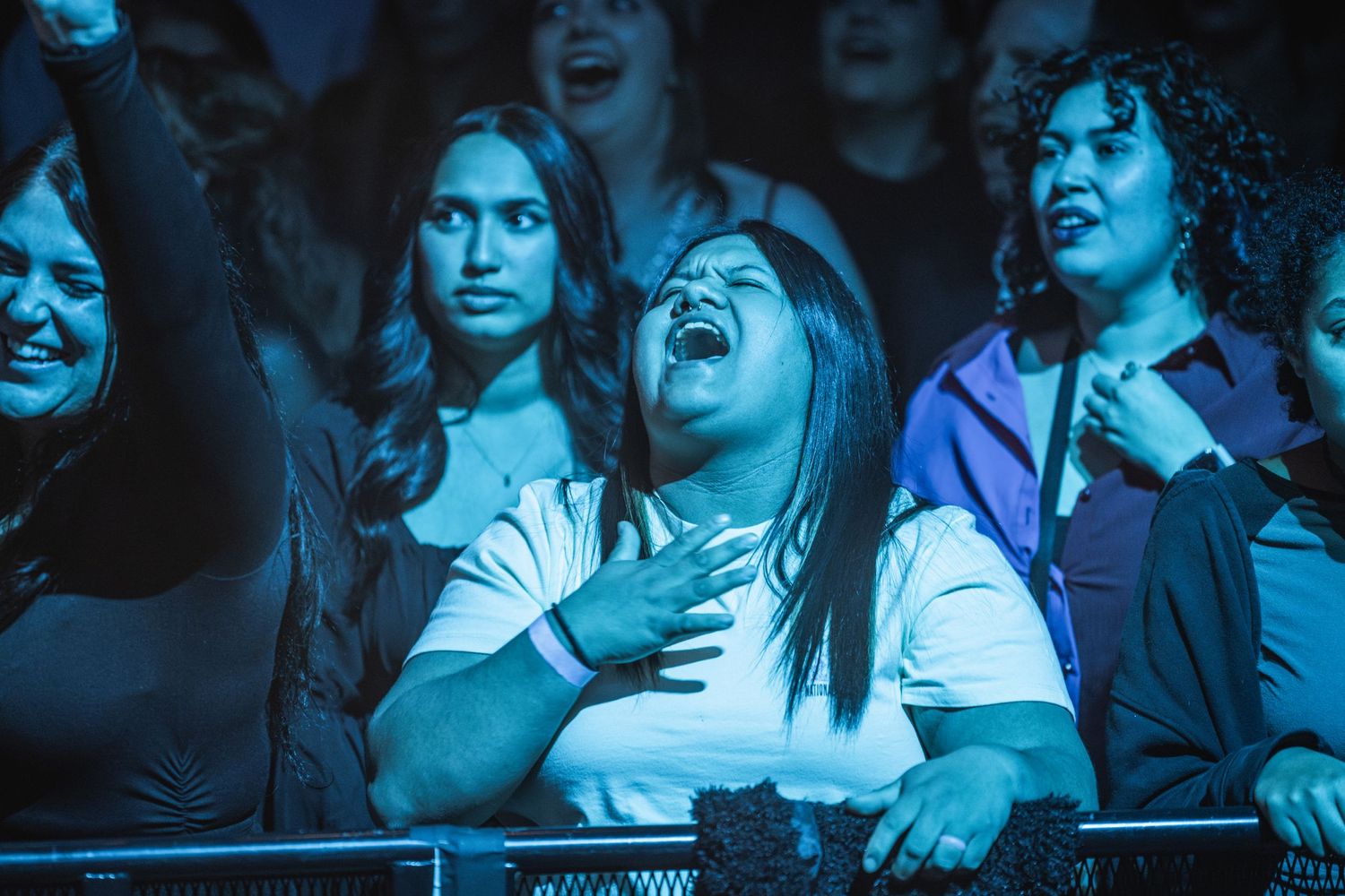 Enthusiastic concert crowd reacting emotionally to performance under blue stage lighting.