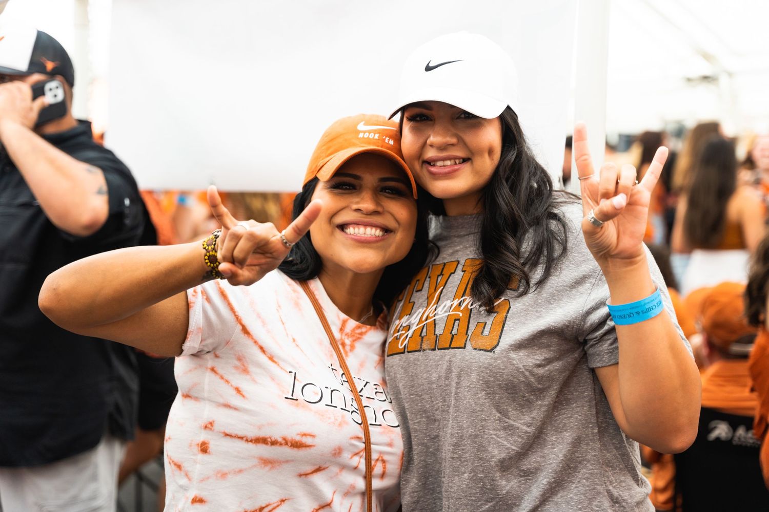 Two friends pose together at outdoor celebration wearing sports team gear.