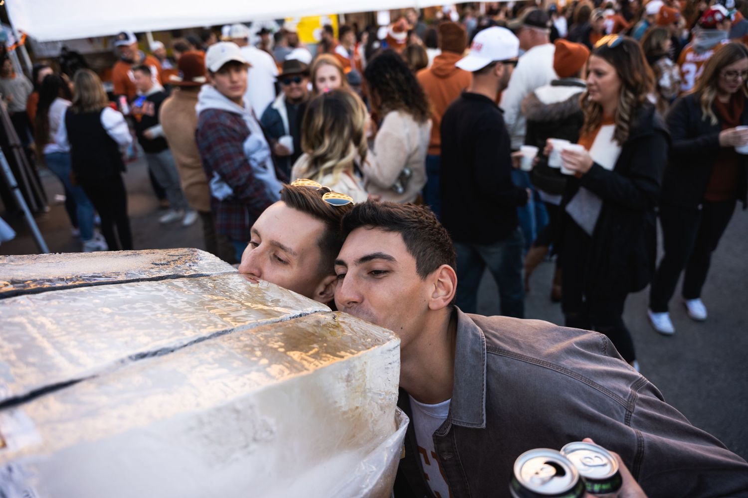People drinking from an ice luge at a crowded outdoor party.