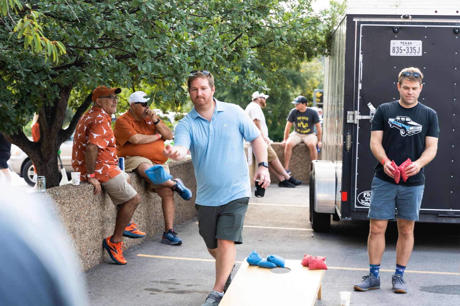 People gathered at an outdoor event with a black trailer in the background.