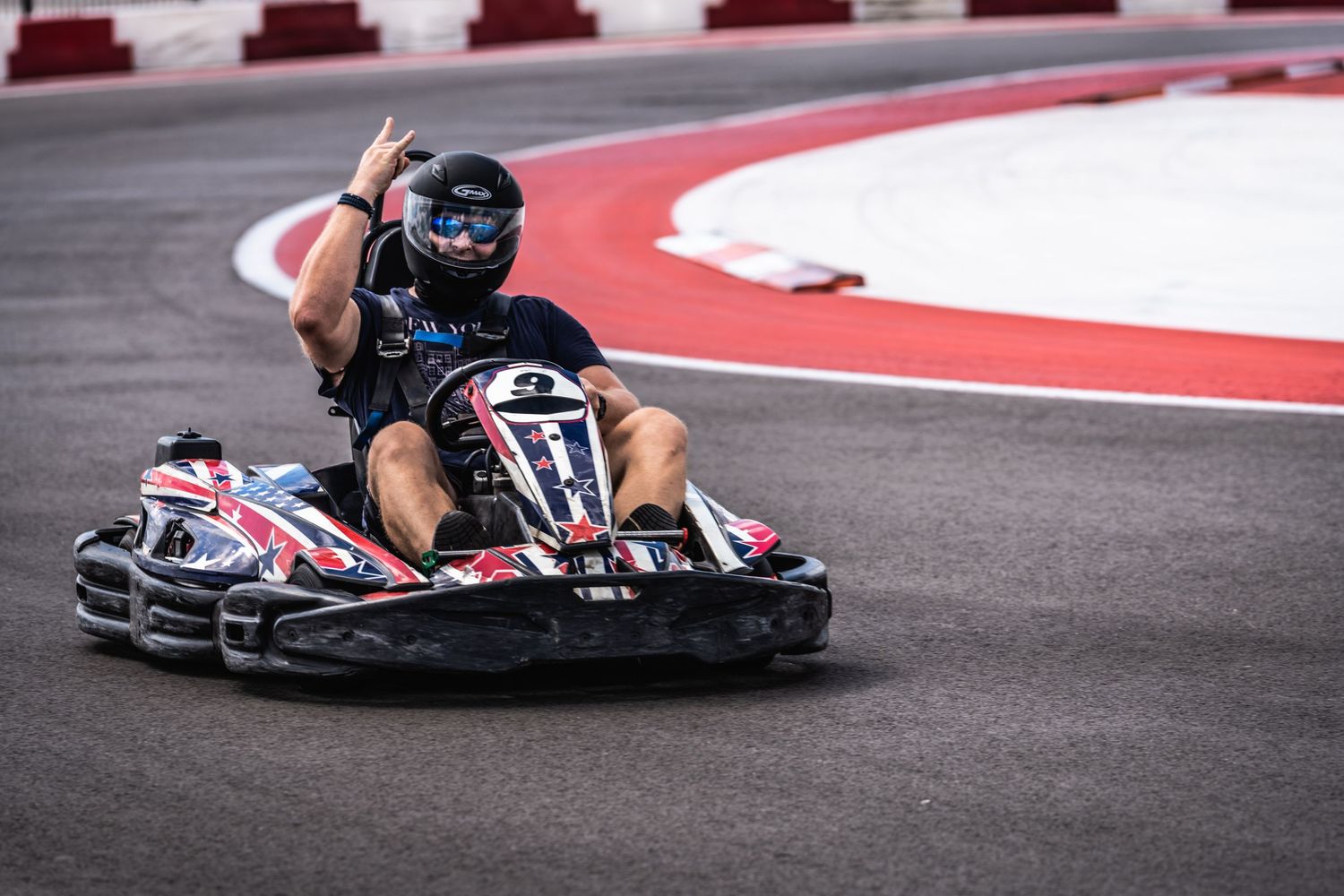 Go-kart racer leaning into a curved section of the track during competition.