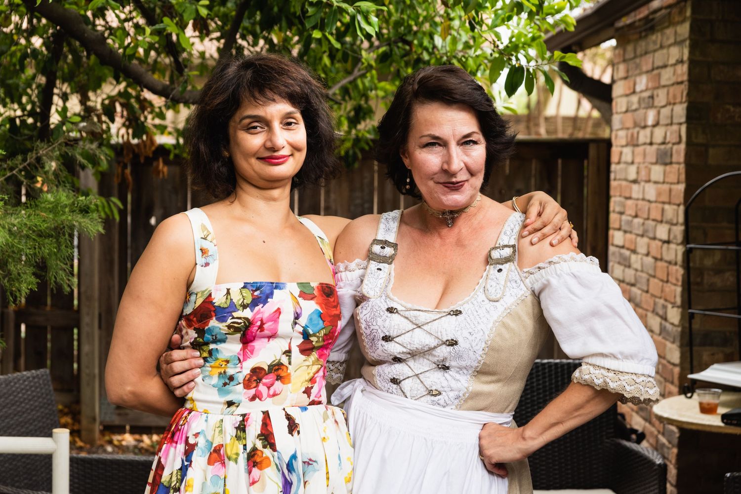 Two people posing together outdoors in summer dresses.