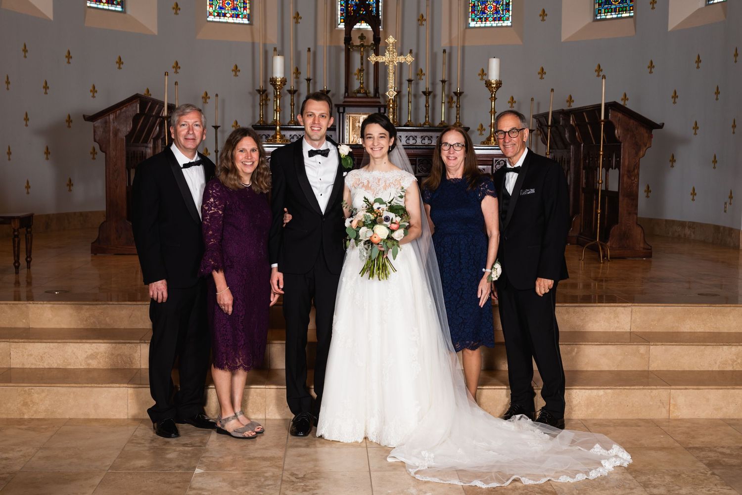 Formal group portrait of wedding party inside traditional church sanctuary.