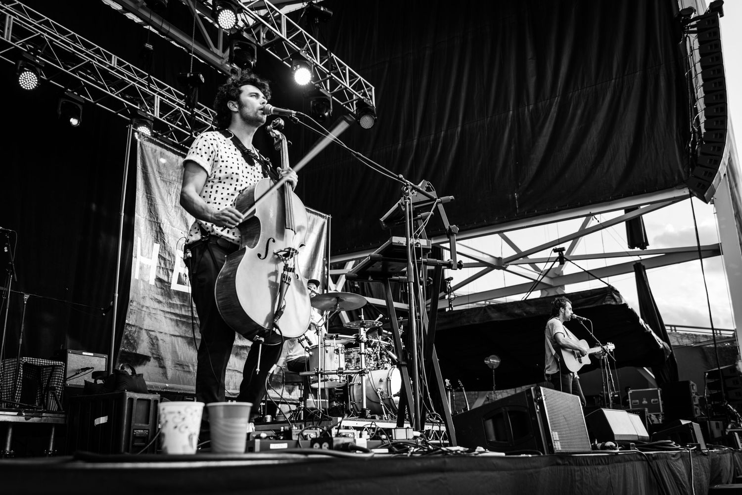 Black and white photo of upright bass player performing on festival stage.