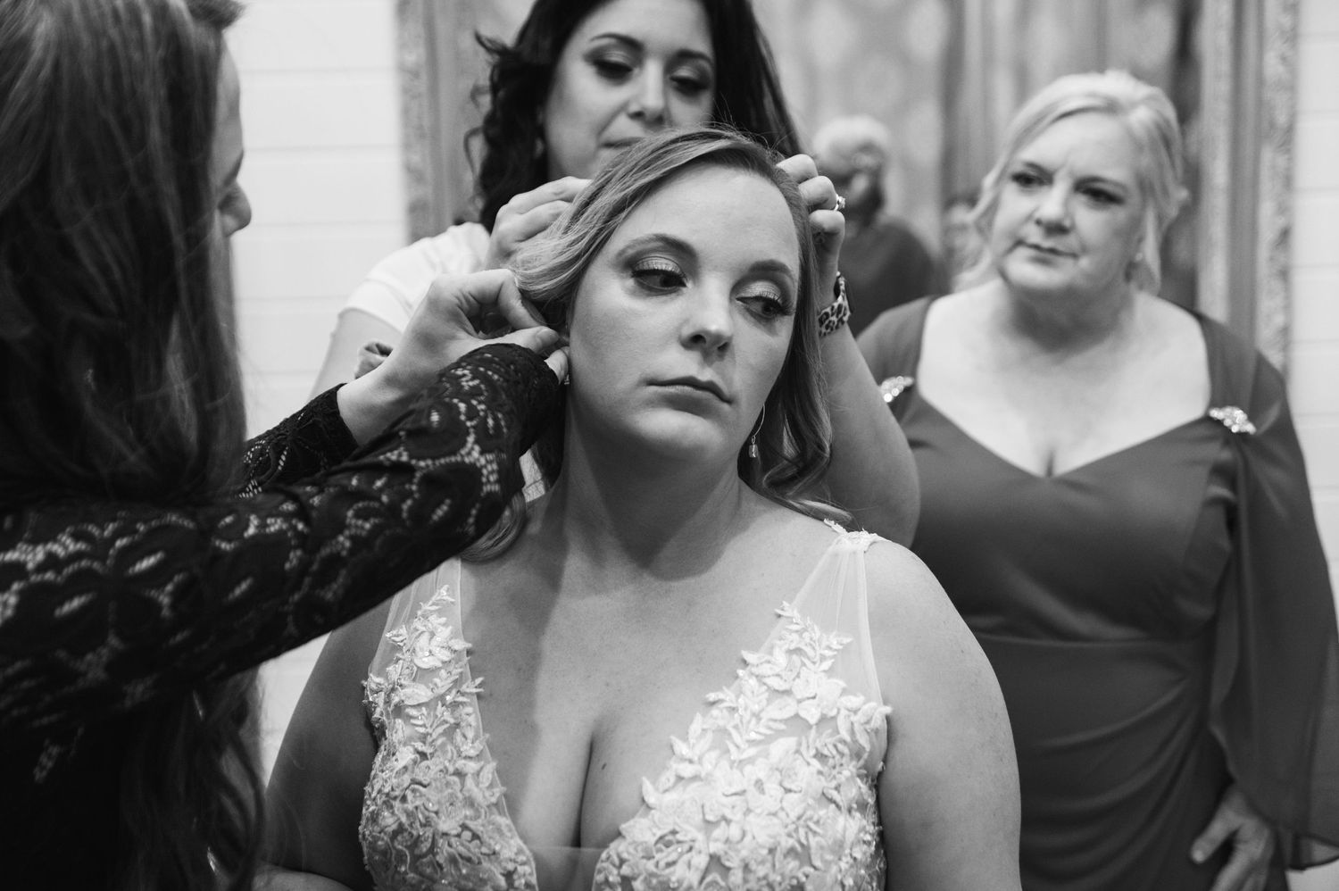 A black and white photo showing final touches being applied to bridal makeup preparations.