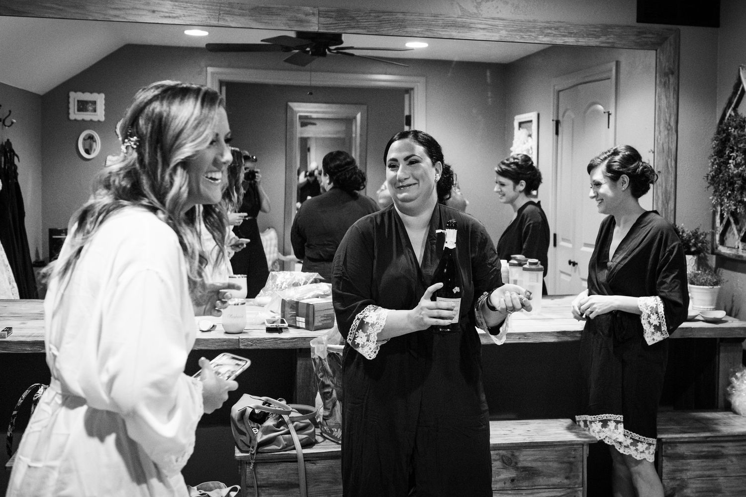 Candid black and white photo of wedding preparations in a dressing room.
